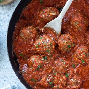 Oven baked meatballs in a skillet with tomato sauce