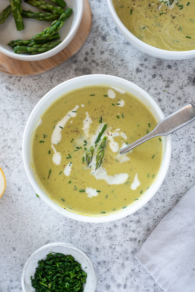 Asparagus soup with cream, asparagus tips and chives on top