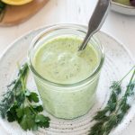 Green goddess dressing in a jar with a spoon