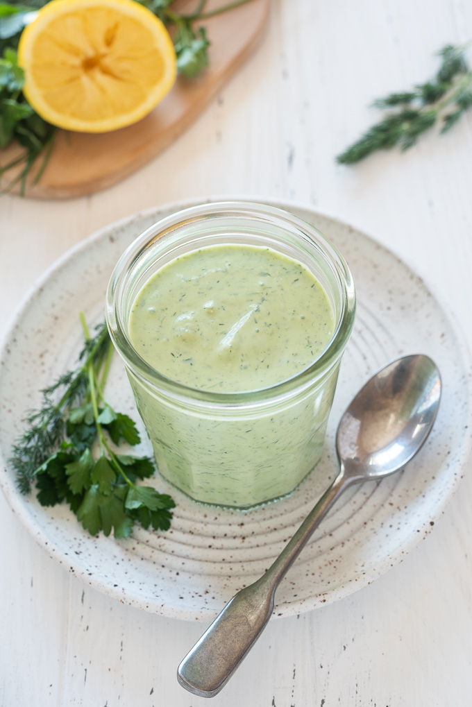 Green Goddess dressing in a jar with herbs and a spoon