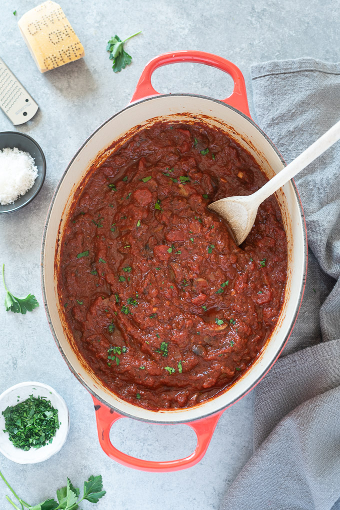Meat sauce in a Dutch oven with a wooden spoon