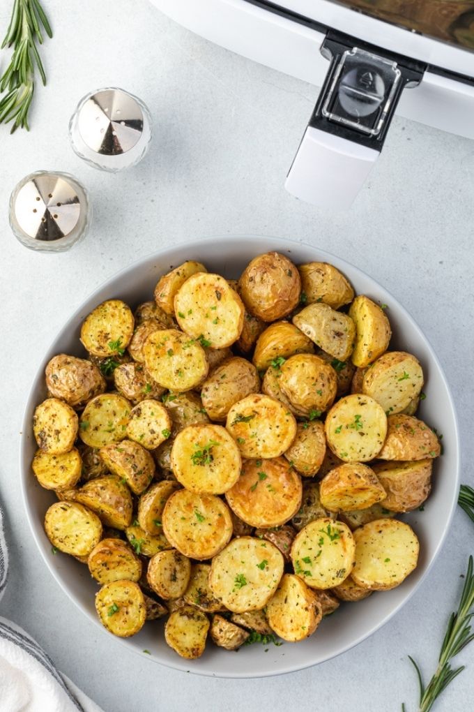Air fryer roasted potatoes in a bowl by an air fryer