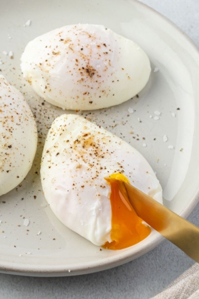 Knife cutting into a poached egg on a plate