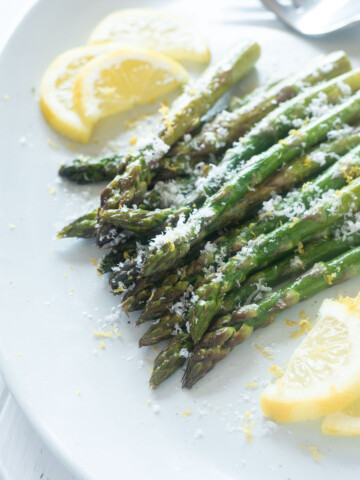 Roasted asparagus on a platter with parmesan cheese on top