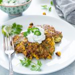 zucchini fritters on a plate topped with yogurt