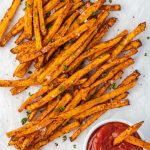 Air fryer sweet potato fries on parchment with ketchup