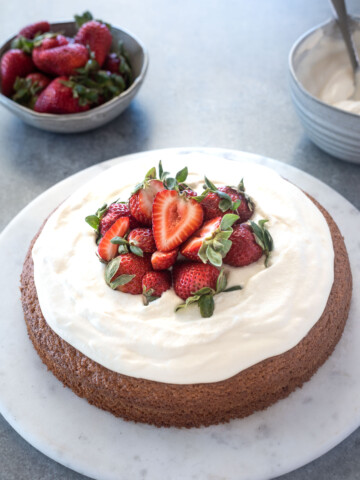 Almond flour cake topped with strawberries and whipped cream