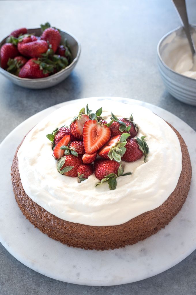 Almond flour cake topped with strawberries and whipped cream