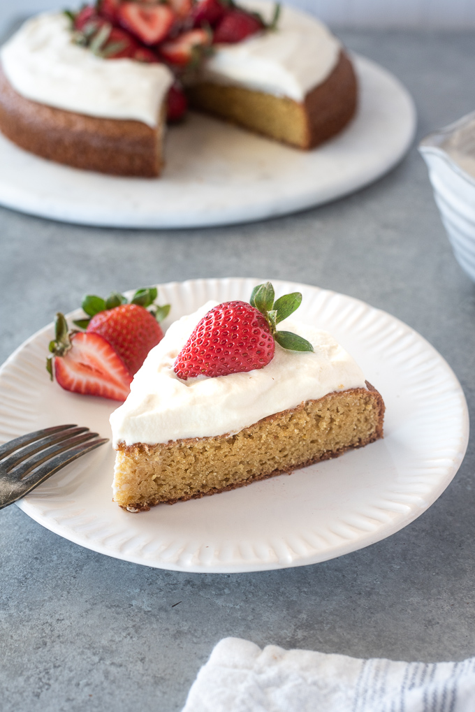 Slice of almond flour cake on a plate with whipped cream and strawberry