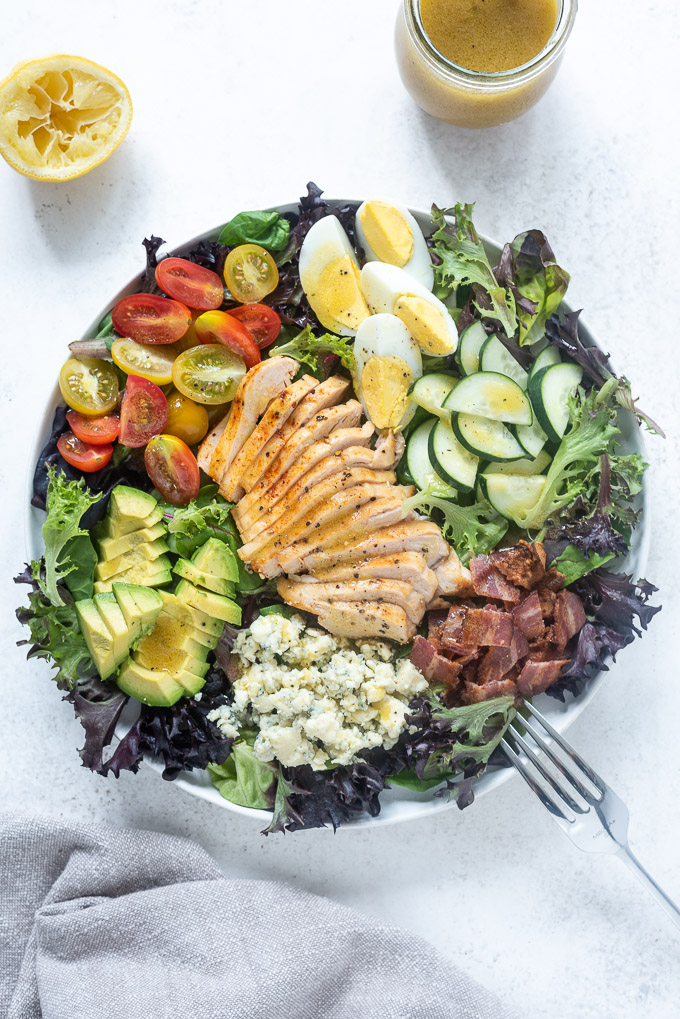 Chicken cobb salad in a white bowl with a fork