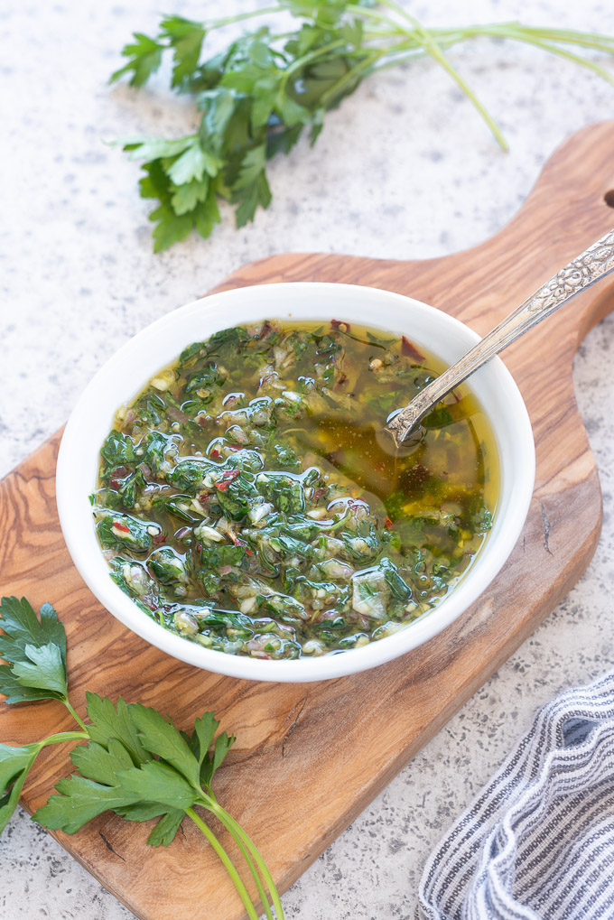 Chimichurri sauce in a bowl on a cutting board