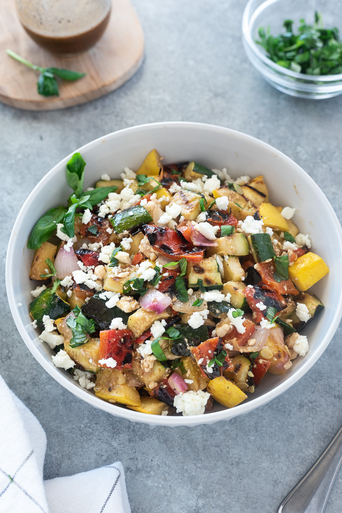 Grilled vegetable salad with feta in a white serving bowl