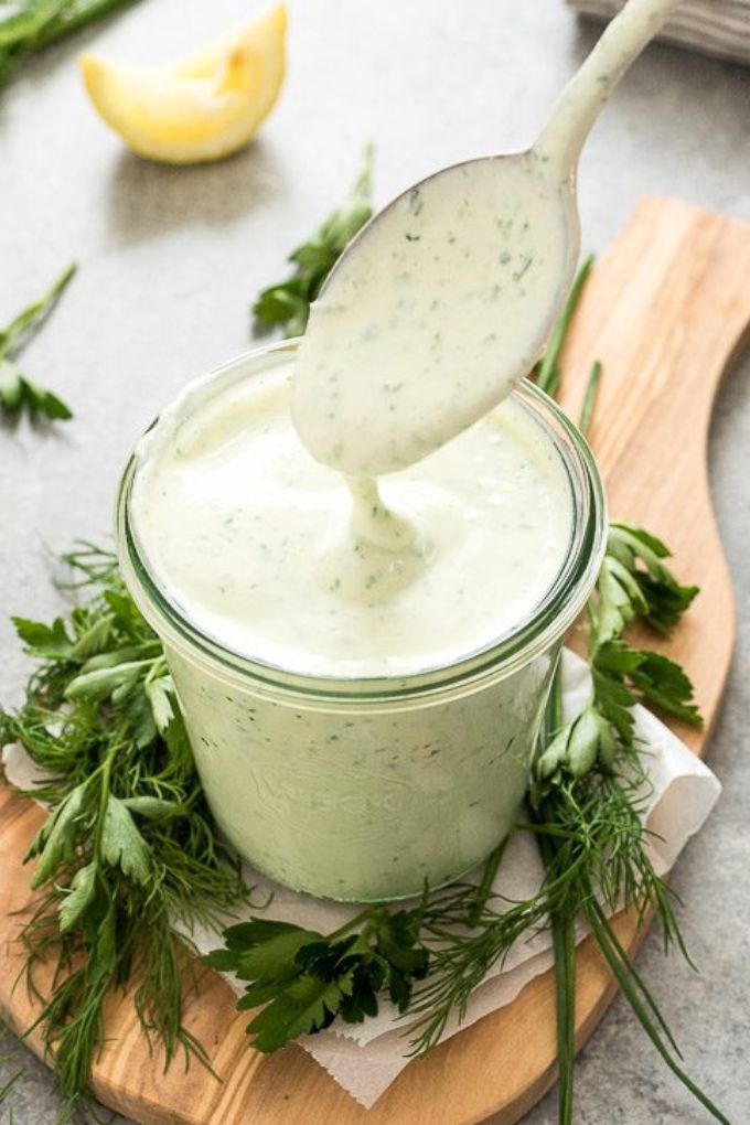 Spoon drizzling Greek yogurt ranch dressing in a jar