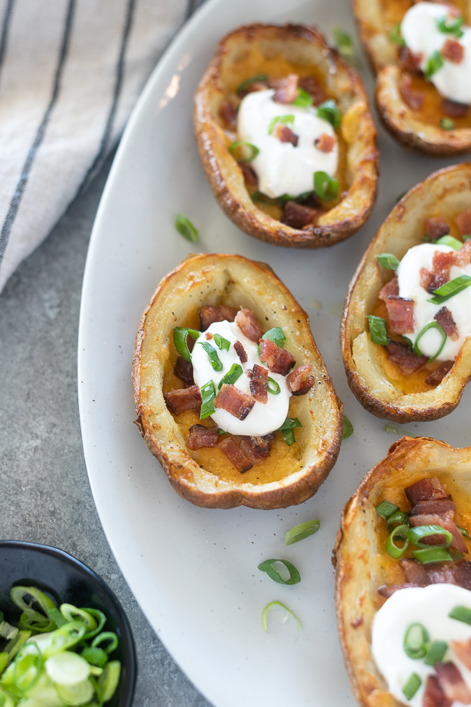 Loaded potato skins on a platter with scallions