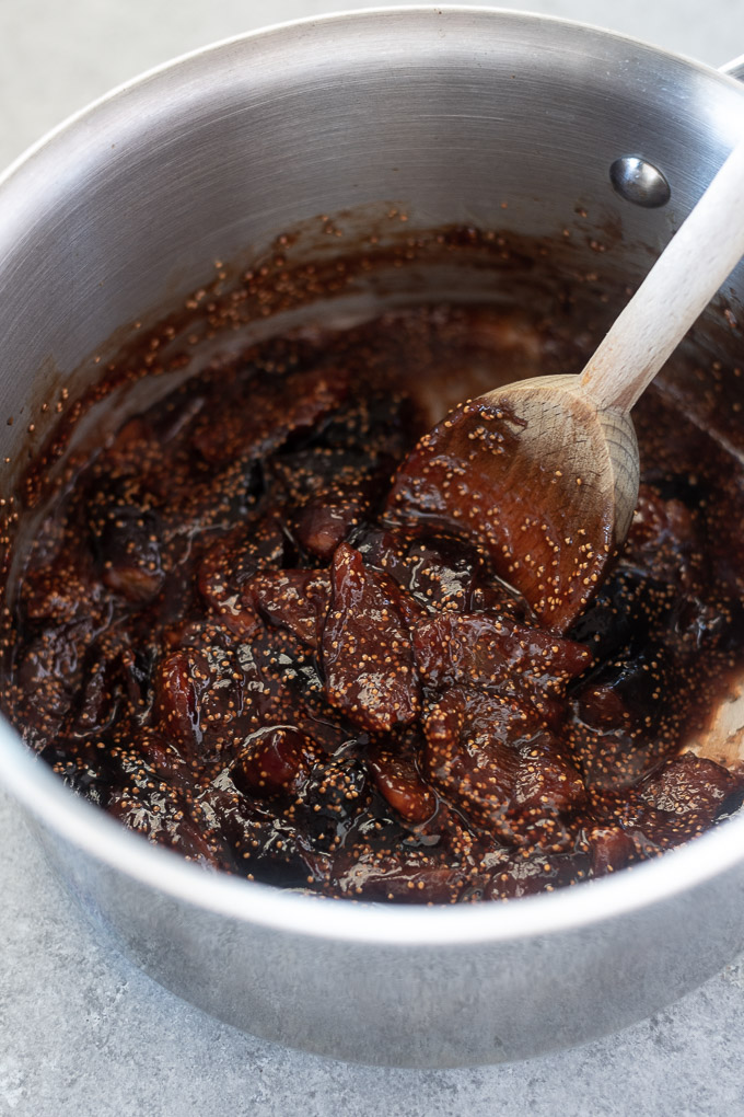 Wooden spoon stirring fig jam in sauce pan