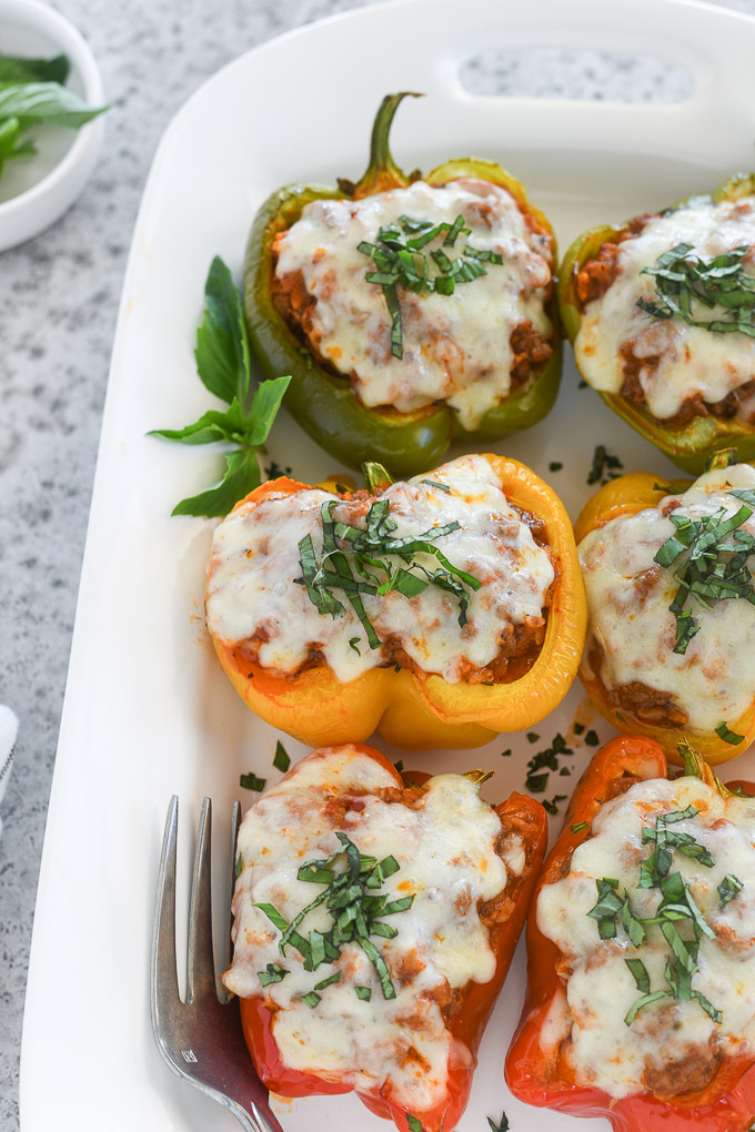 Italian stuffed peppers on a serving platter with basil
