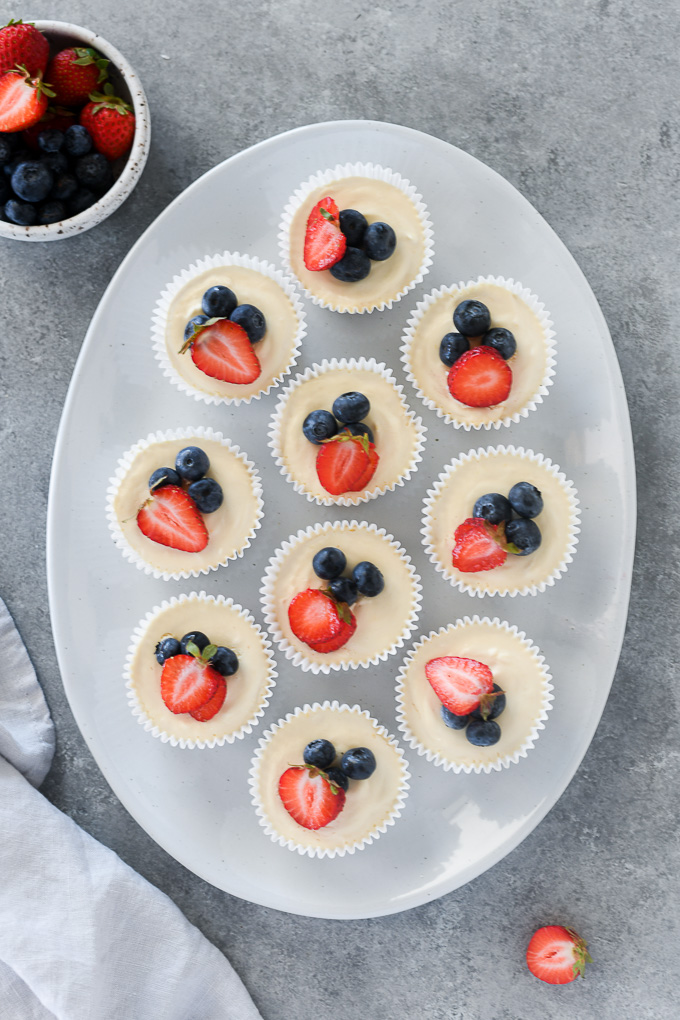 Mini no bake cheesecakes on a platter topped with berries