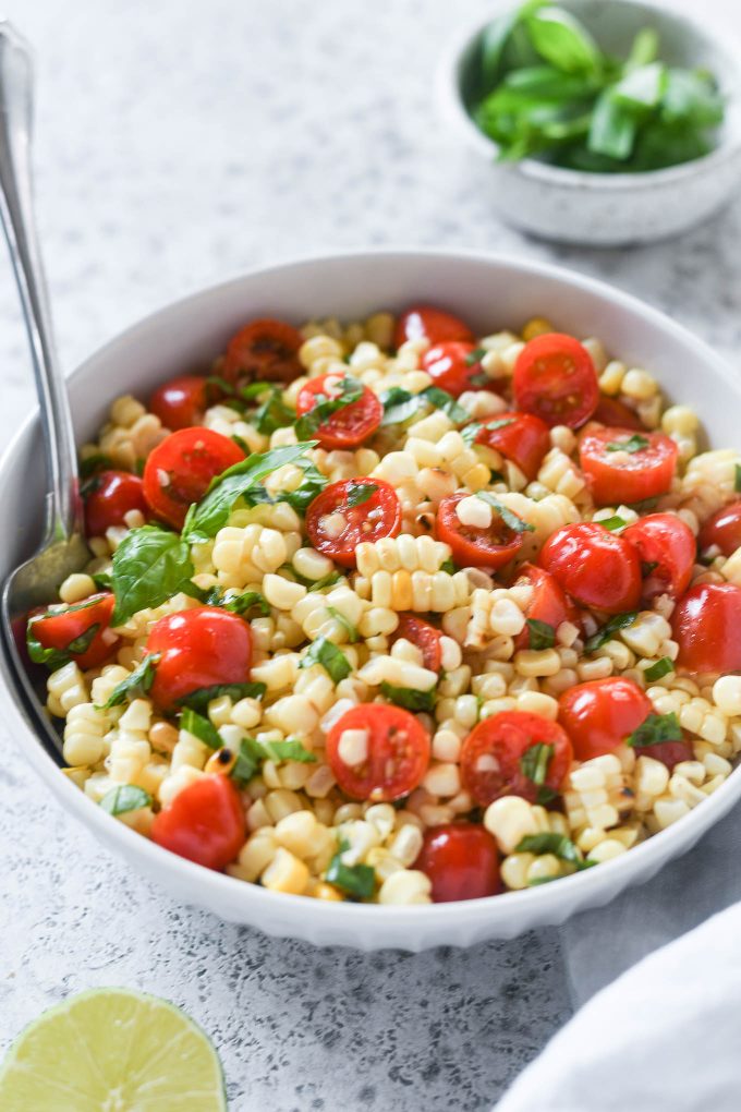 Spoon buried in a bowl of corn and tomato salad