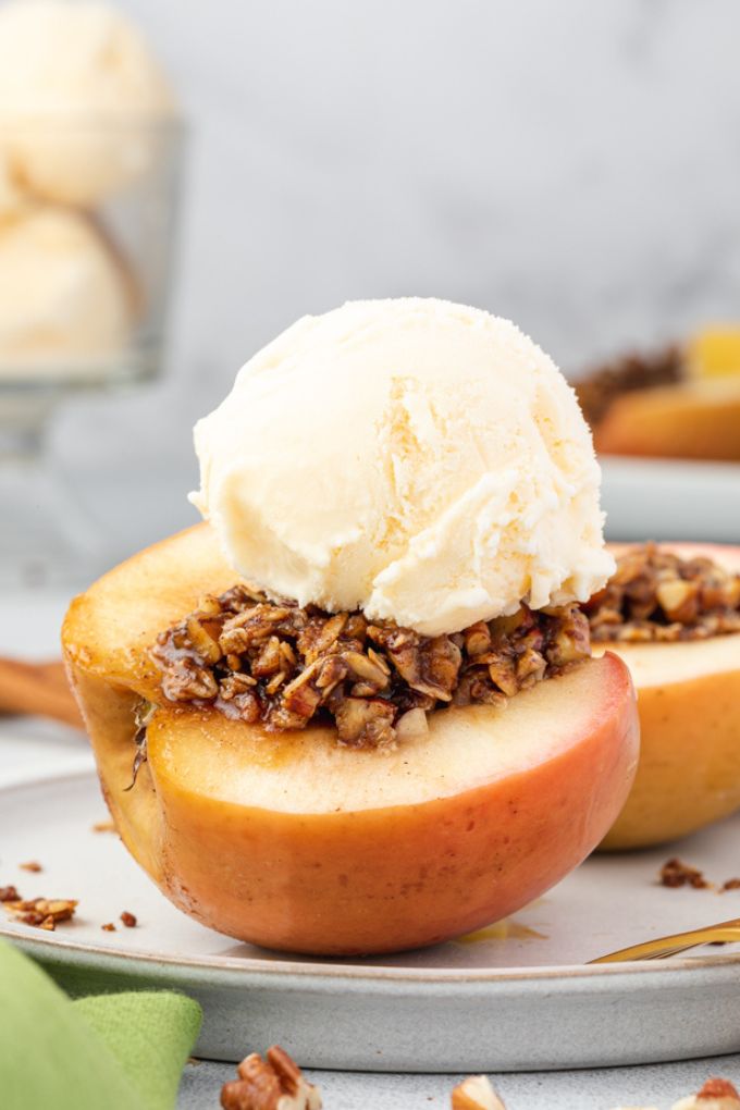 Baked apples cut in half on a plate with ice cream