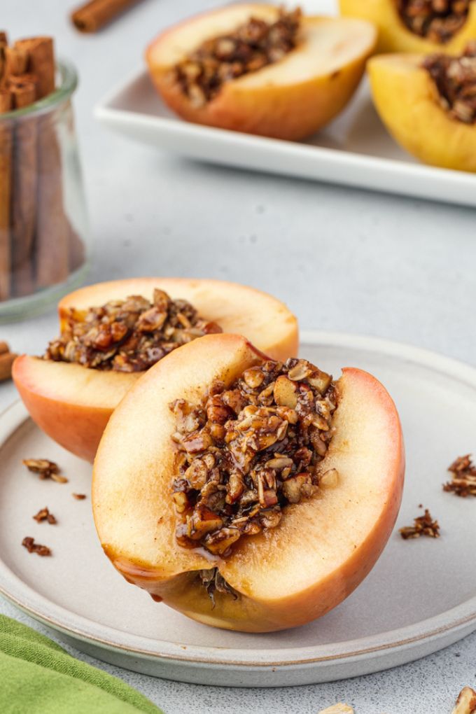 Baked apple cut in half with oat pecan filling in the middle