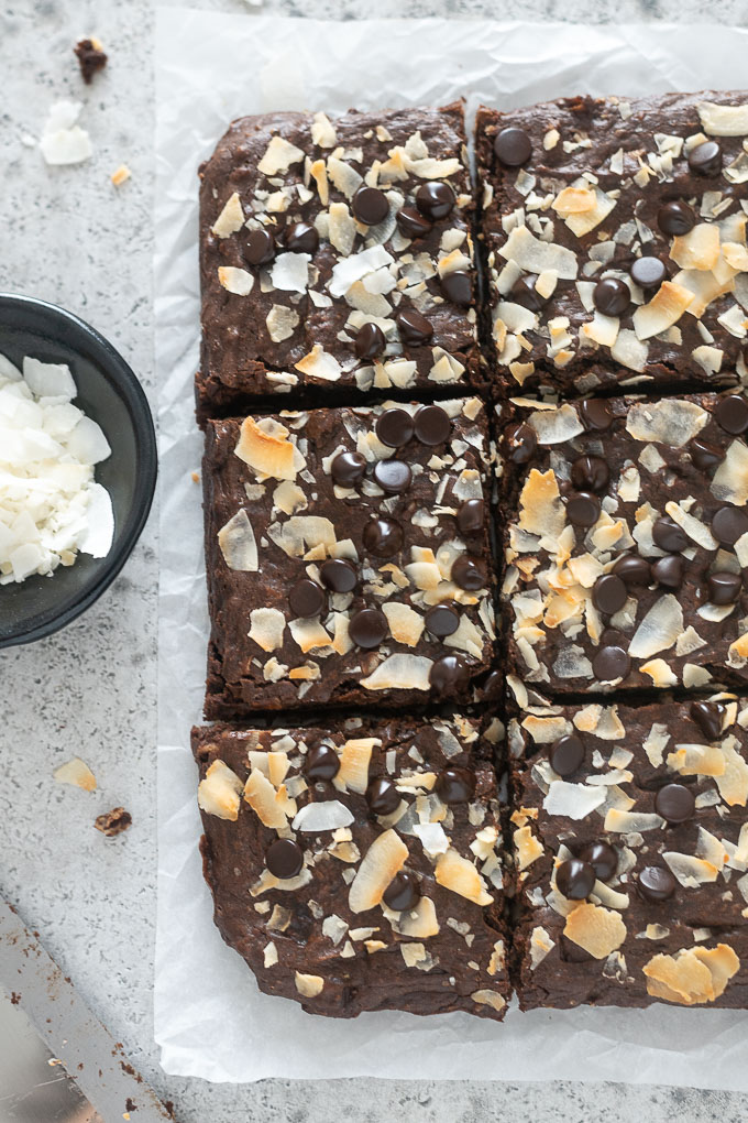 Coconut brownies cut into squares on parchment