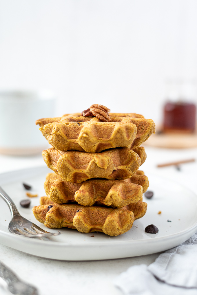 Pumpkin waffles on a plate with pecans on top