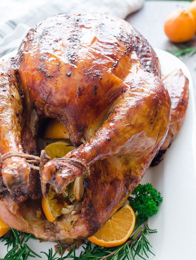 Orange rosemary roast turkey trussed on a white platter