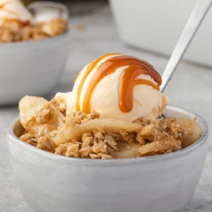 Pear crumble in a bowl with ice cream and caramel