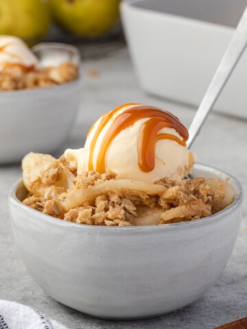 Pear crumble in a bowl with ice cream and caramel