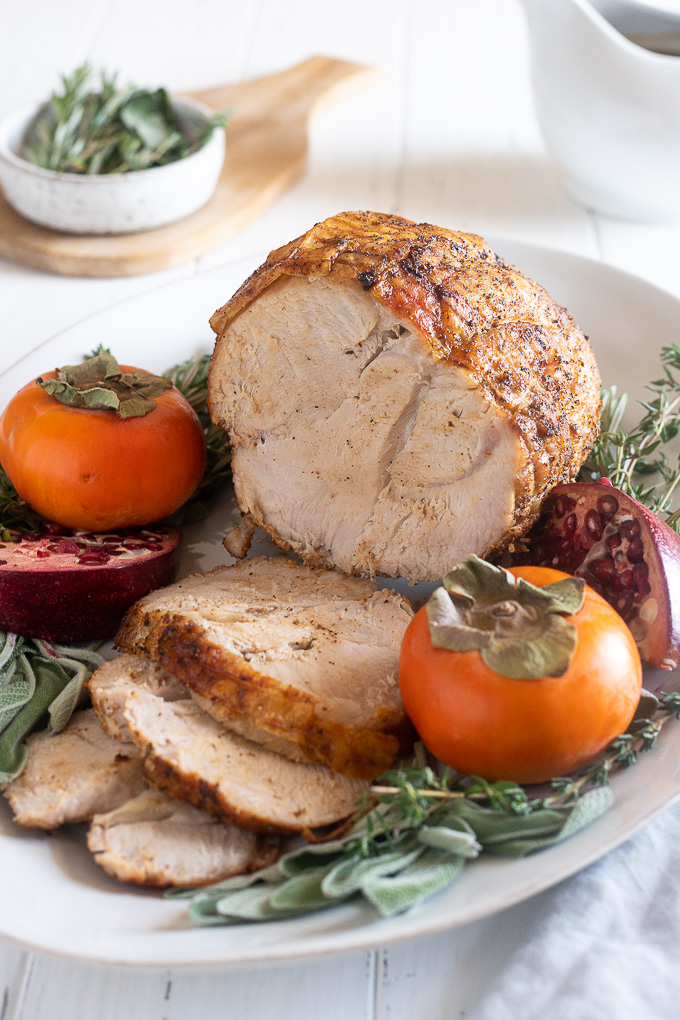 Turkey breast roast on a platter with herbs and fruit