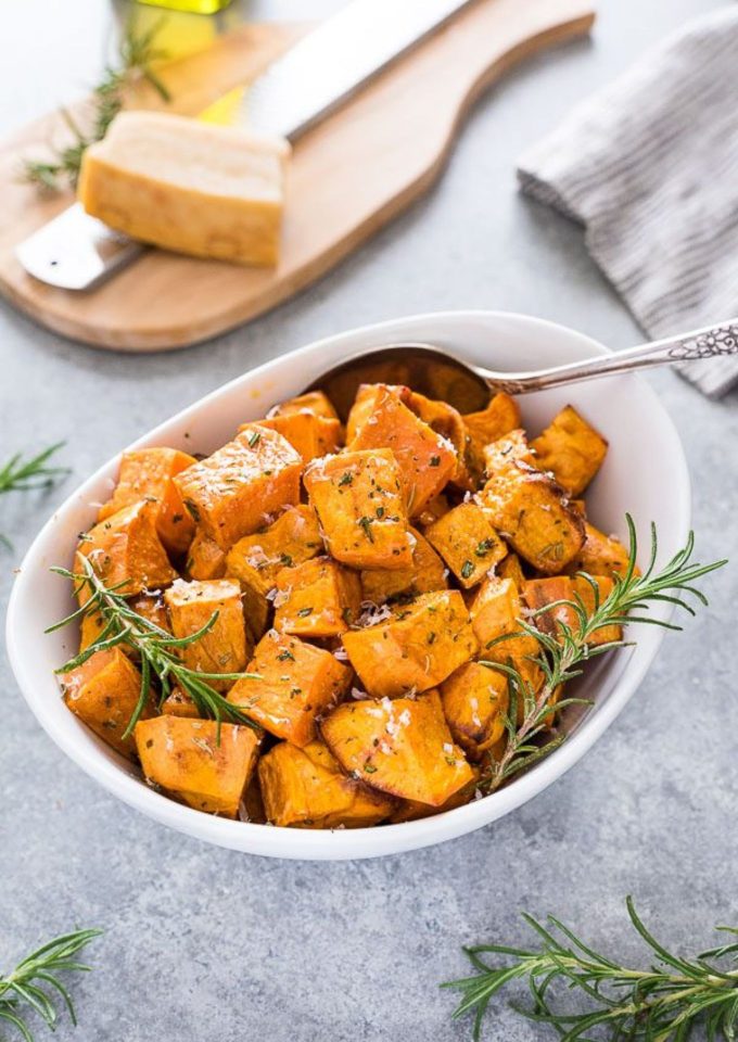 Roasted sweet potatoes in a white bowl with rosemary