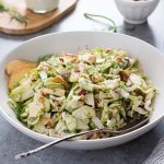 Shaved brussels sprout salad in a bowl with serving spoon