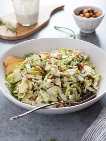 Shaved brussels sprout salad in a bowl with serving spoon