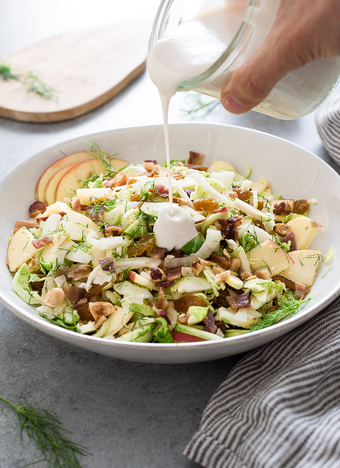 Shaved brussels sprout salad with dressing pouring over it