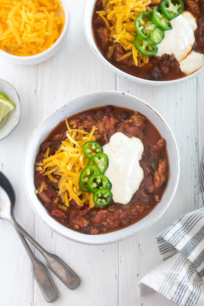 Bowl of slow cooker turkey chili loaded with cheese, sour cream and jalapenos