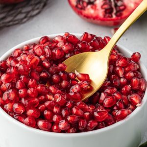 Spoon digging into bowl of pomegranate seeds