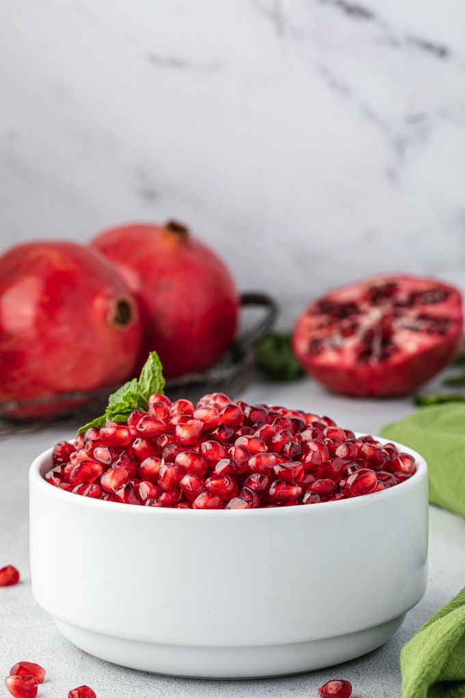Pomegranate seeds in a white bowl with mint