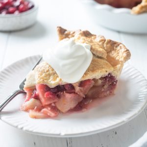 Slice of apple cranberry pie with whipped cream