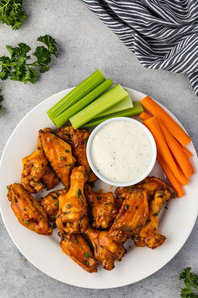 Honey buffalo chicken wings on a platter with veggies and ranch