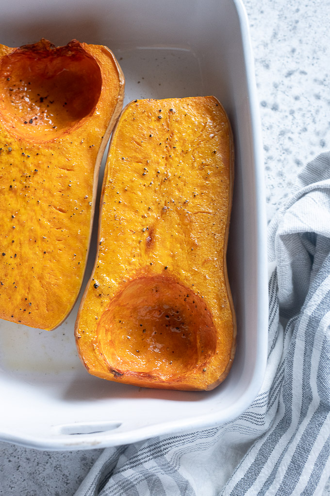 Roasted butternut squash halves in a baking dish
