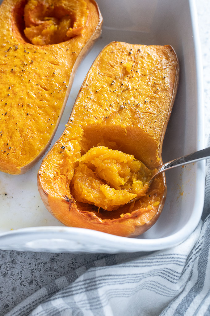 Spoon scooping flesh out of whole roasted butternut squash