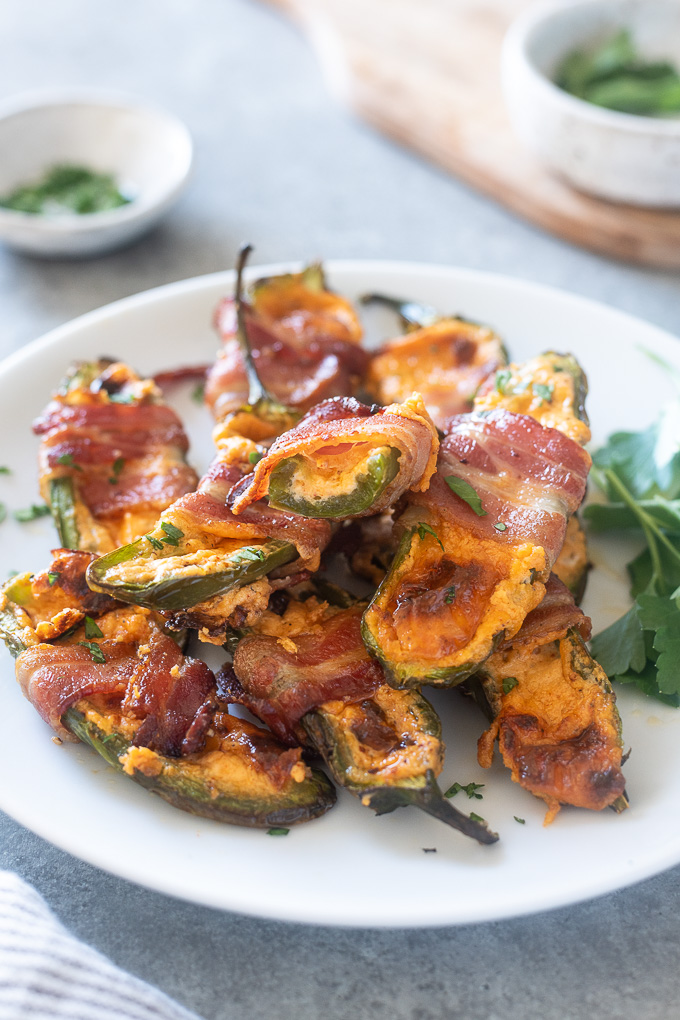 Bacon wrapped jalapeno poppers piled on a plate