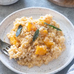 Baked butternut squash risotto on a plate with crispy sage leaves