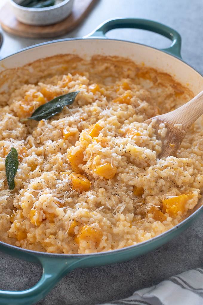 Wooden spoon in pan of butternut squash risotto