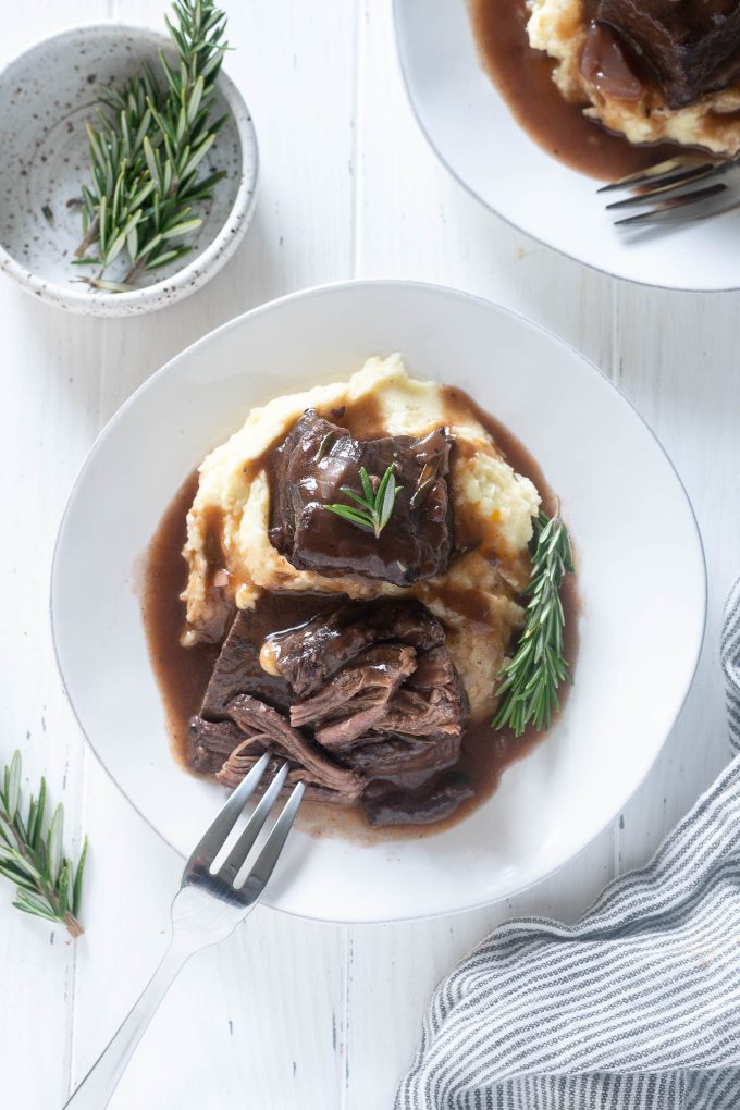 Red wine braised short ribs on a plate with fork pulling meat
