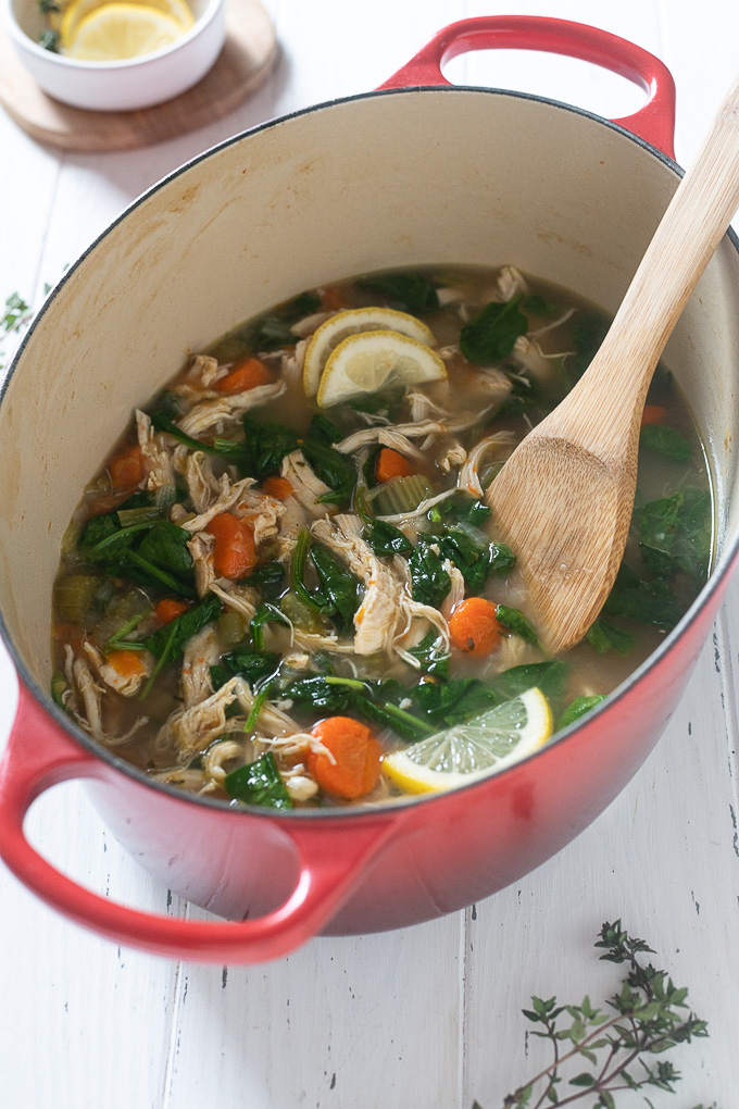 Chicken vegetable soup in Dutch oven with wooden spoon
