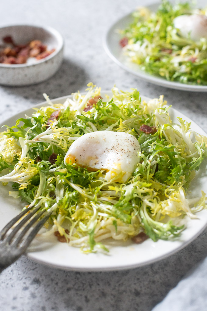 Lyonnaise salad on a plate with broken egg yolk
