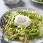 Salade lyonnaise on a plate of frisée lettuce