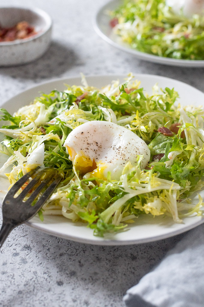salade lyonnaise with fork breaking yolk