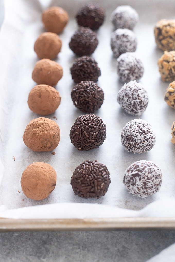Dark chocolate truffles rolled in coatings on a baking sheet